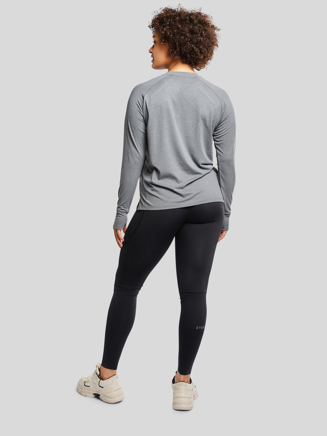 kvinde bagfra med træningstrøje i farven dark grey og sorte tights