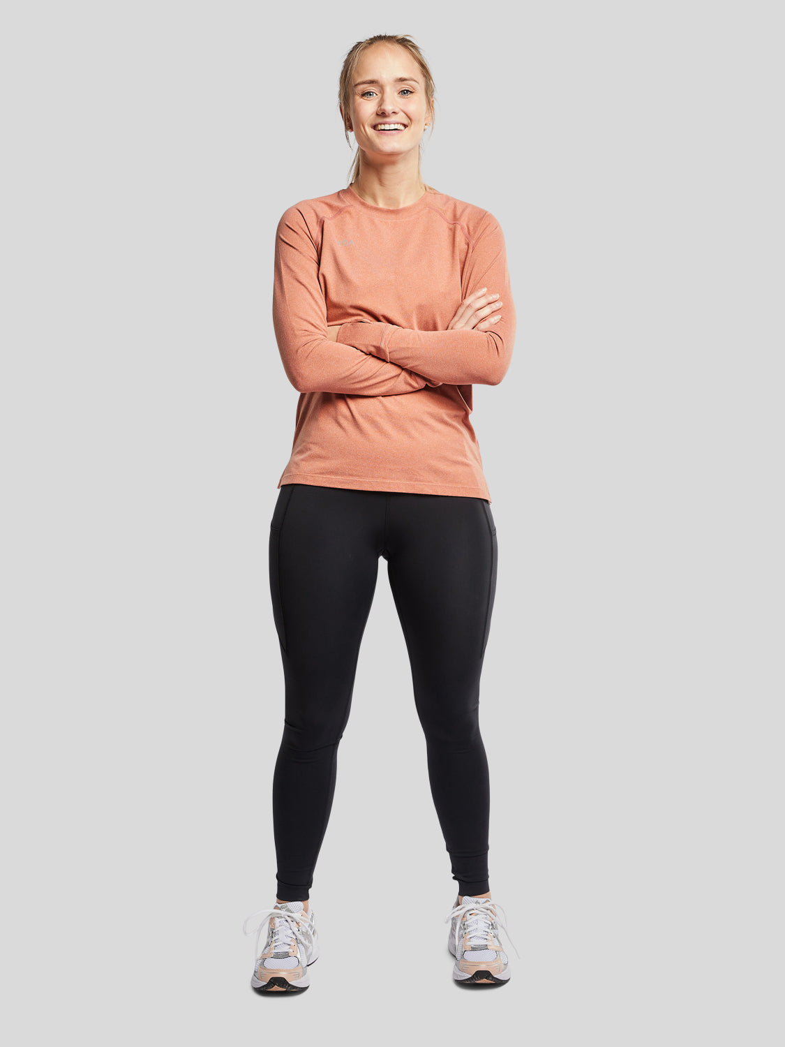 kvinde forfra med træningstrøje i farven rust og sorte tights