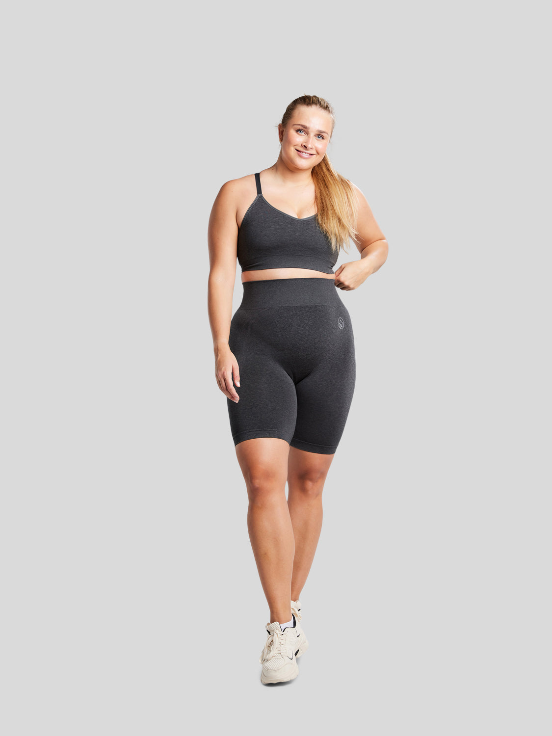 kvinde forfra i fuld figur med seamless shorts og sports bh i farven black melange